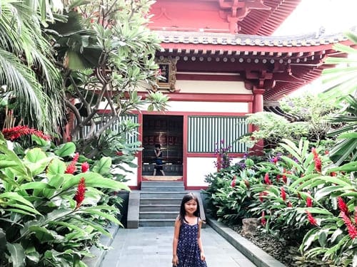 A young girl stands in front of hte Buddha Tooth Relic Temple in Singapore.