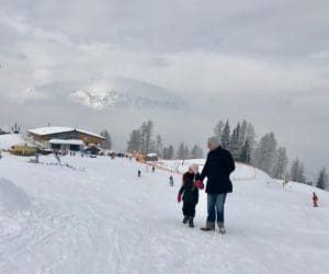 Father and daughter walk along a ski hill in Alpendorf, Austria.