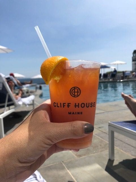 A hand reaches out and holds an alcoholic drink at Cliff House Maine.