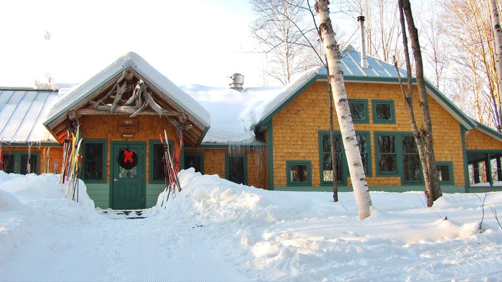 The snow-covered Flagstaff Hut at Maine Huts And Trails, one of the best places to stay for families. It's also one of the best places on our family guide to skiing the Maine Huts and Trails