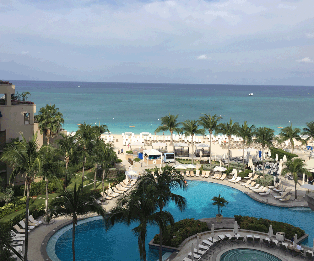 Pool and ocean with palm trees at Grand Cayman resort