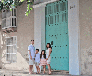 A family of four stands in front of a turquoise door in Cartagena's Old City.