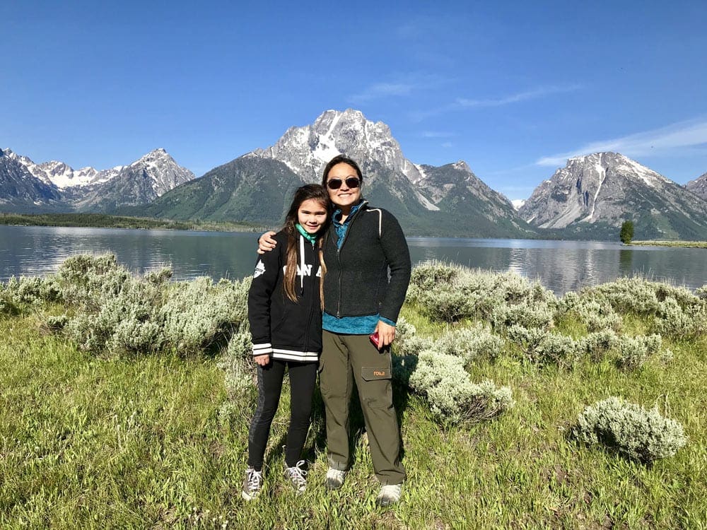 Mom and daughter in Tetons National Park, with mountains behind them.