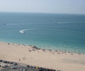 Boats in water and people on beach at Jumeirah Beach in Dubai