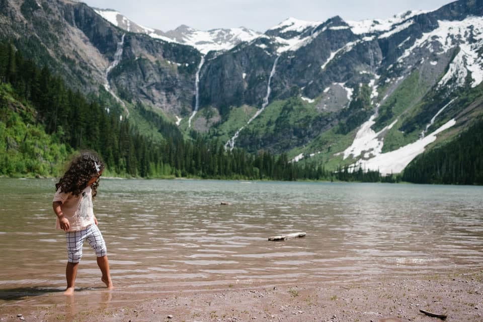 Girl in the lake in Glacier National Park, one of the best national parks for families.