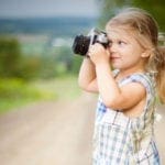 Young girl in dress taking a picture with a professional camera
