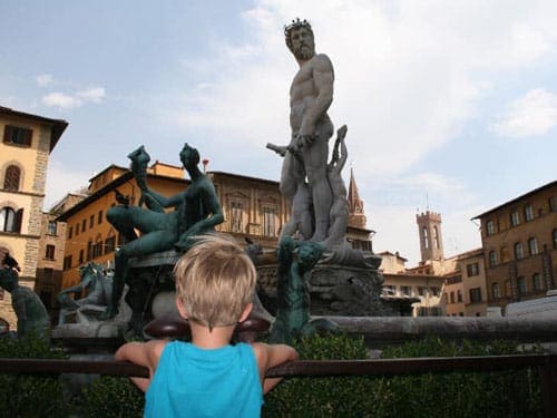 A young boy looks at a large statue in Florence.