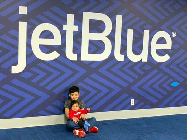 Children in front of U.S. airline sign for JetBlue