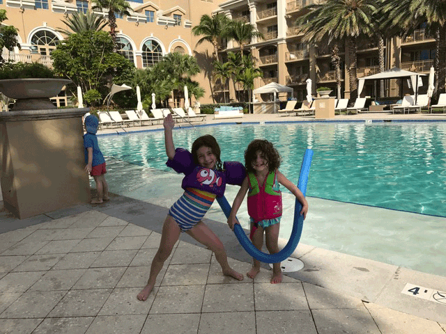 Two sisters with floaties and pool noodle by pool at Ritz-Carlton, Grand Cayman