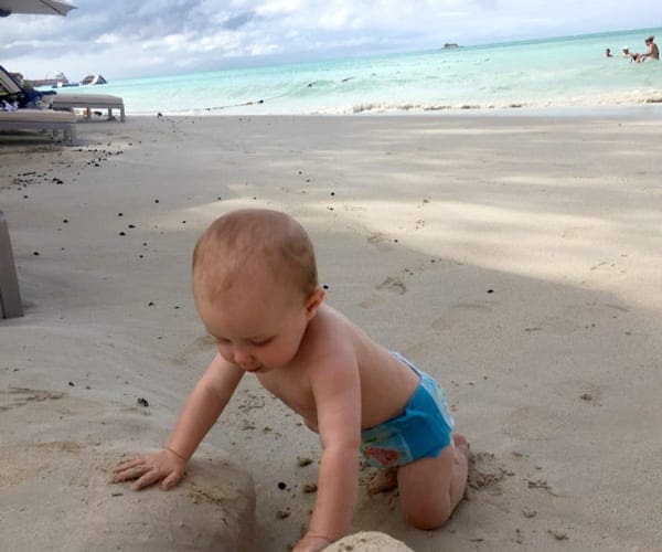 Baby in swim diaper playing in sand on beach in Antigua