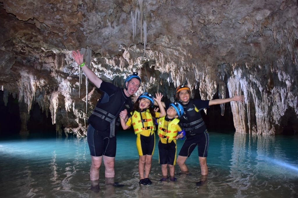Family with two children in wetsuits posing in underground caves in Rio Secreto