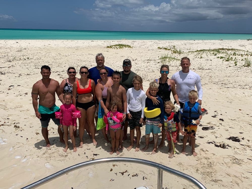 A multi-generation family stands on the beach in front of the ocean at Beaches Turks & Caicos.