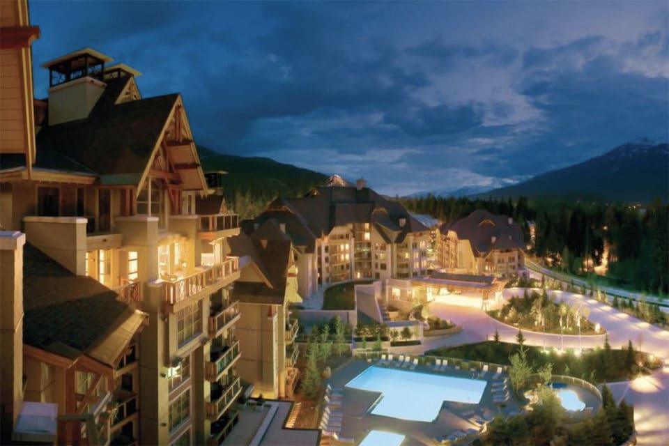 Aerial view of Four Seasons Resort Whistler, one of the best family hotels in Whistler, featuring pine trees and an outdoor pool.