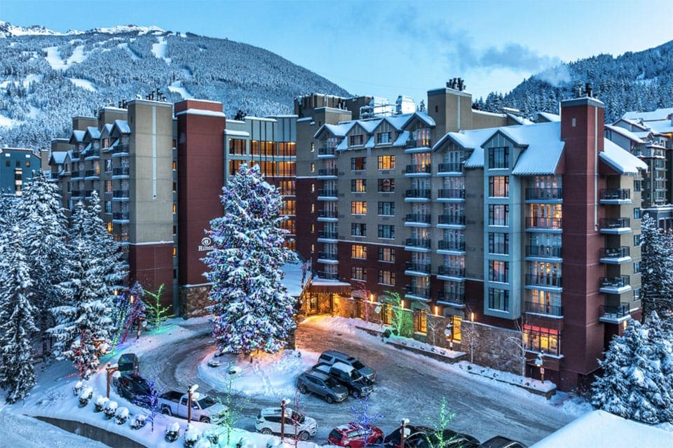 Hilton Whistler Resort & Spa, one of the best family hotels in Whistler, during the winter, covered in snow.