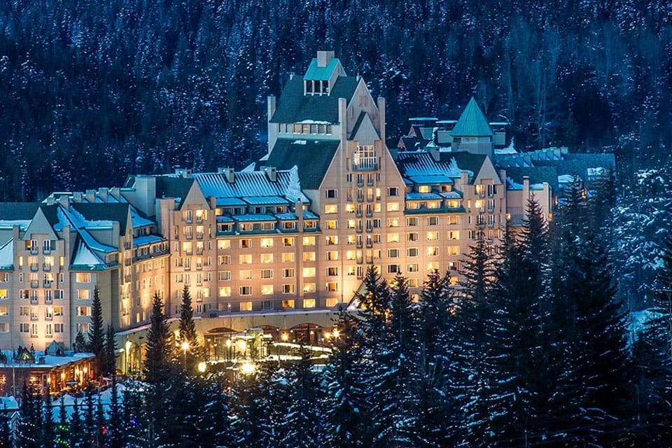 Hotel Fairmont Château Whistler, one of the best family hotels in Whistler, at night during the winter, showered in bright lights.
