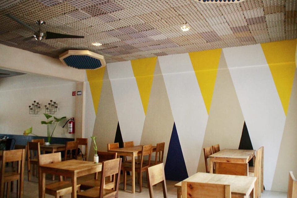 Inside Lara Y Luca, one of the best restaurants in Playa del Carmen with kids, featuring intimate wooden tables, and yellow accented walls.