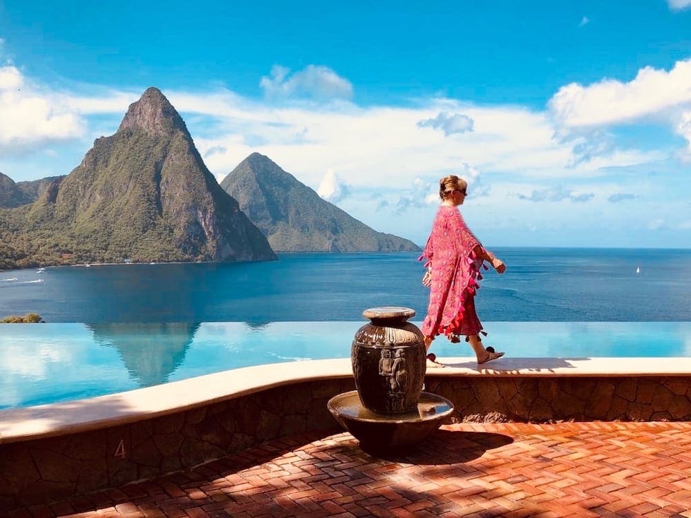 A woman walks across a ledge at the hotel with the pitons of Saint Lucia in the background.