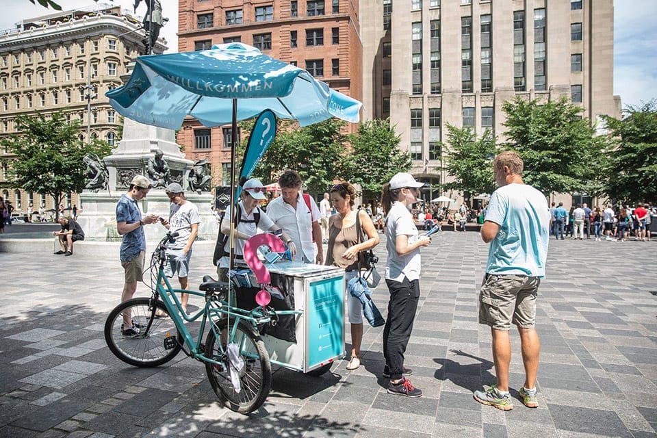 People order from a bike cart selling treats inside a square in Old Montreal.