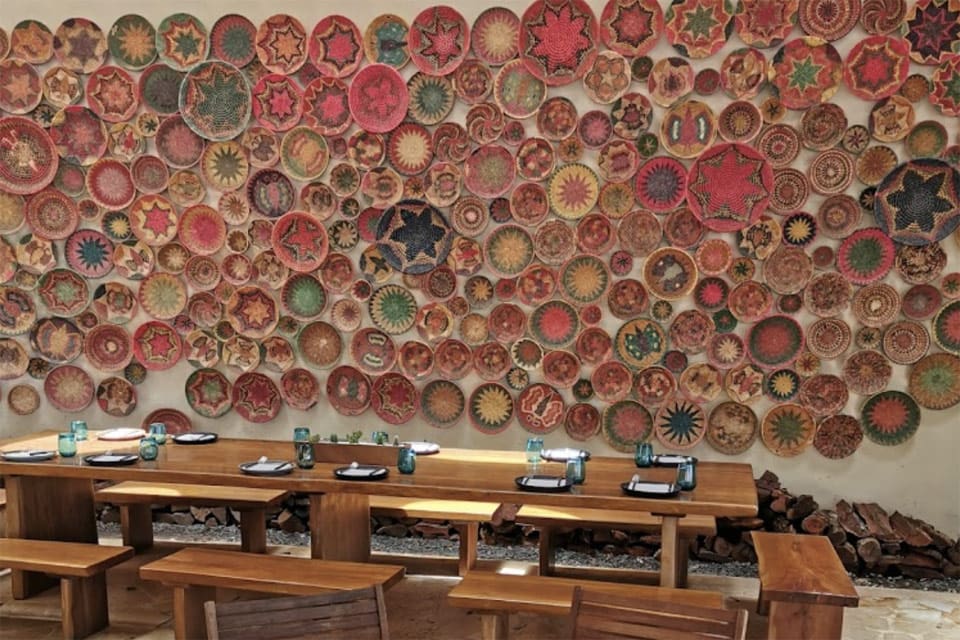 Inside Punta Bonita, featuring a long table and numerous colored bolws decorating the wall behind the table.