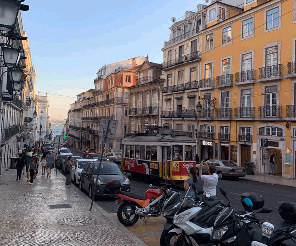 A street in Lisbon, featuring several cars and beautiful architecture.