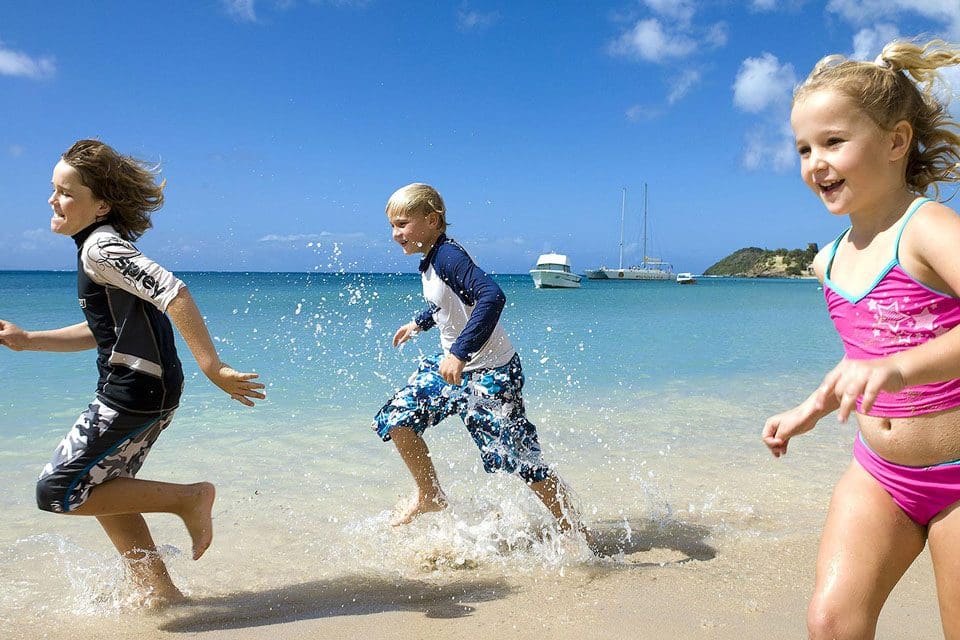 Three kids run and splash in the water at Curtain Bluff.