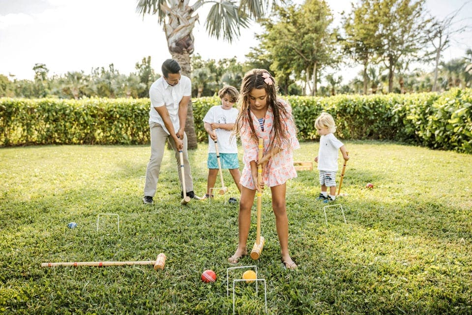 Three young kids play croquet with their father at COMO Parrot Cay, Turks and Caicos.