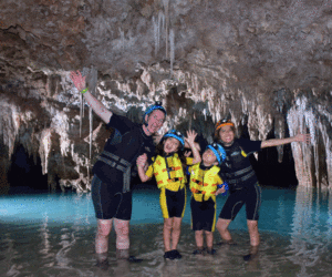A family of four stands together in a cave while on a tour in Playa del Carmen.