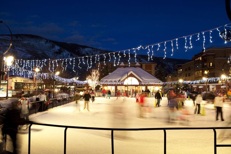 An outdoor skating rink in Aspen, filled with families and onlookers.