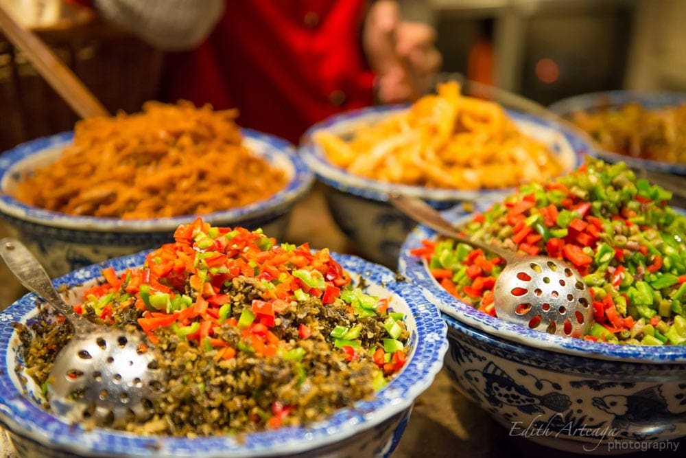 Several bowls piled high with traditional Chinese cuisine, including fride rice. Making Chinese-inspired dishes is a delicious way to take a virtual vacation to China.