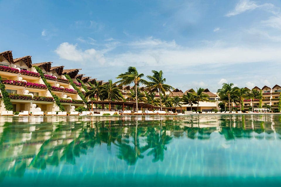 The large pool at Grand Velas Riviera Maya, with resort buildings in the background, one of the best all-inclusive resorts Playa del Carmen 
for families.