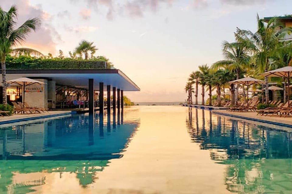The infinity pool of Hotel Xcaret during sunset, one of the best all-inclusive resorts Playa del Carmen for families.