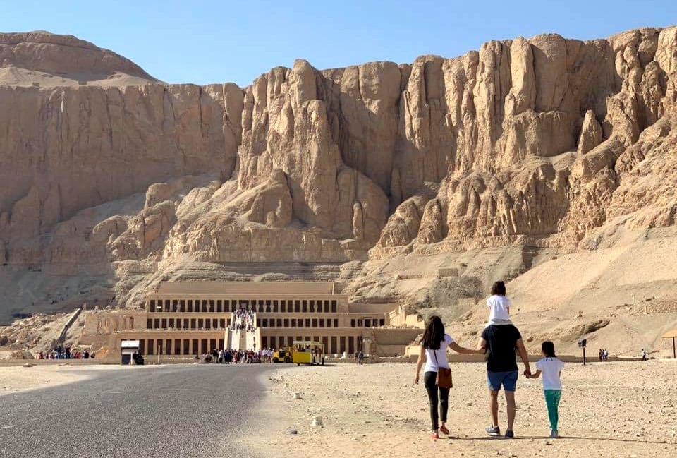 A family of four walking along the desert toward an Egyptian sight, one of the best weekend getaways from Dubai for families.