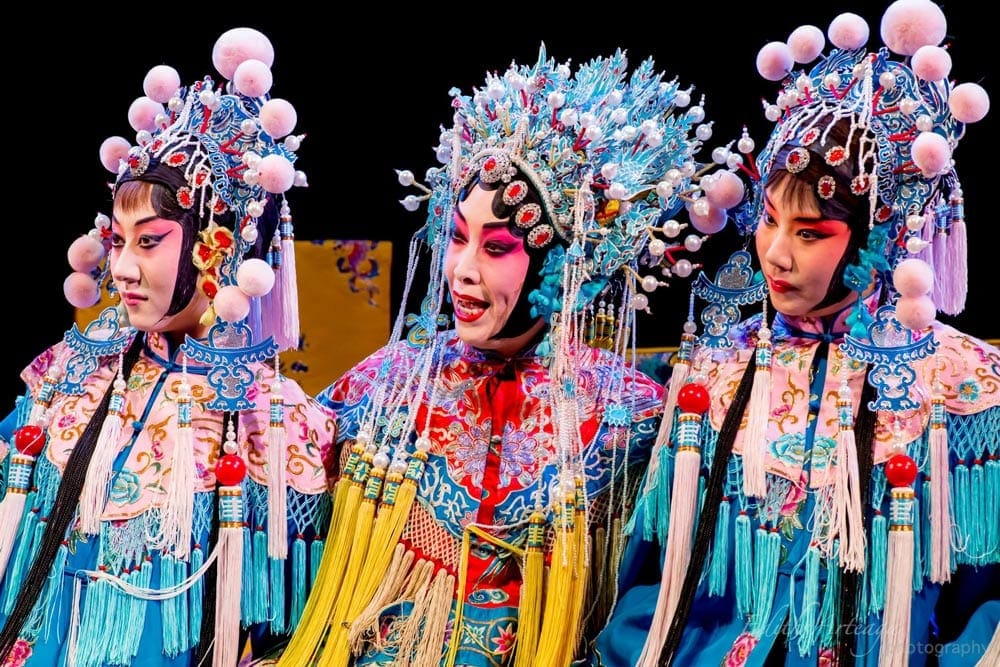 Three women preform in full costume at the Peking Opera House in Beijing China. Music is a great way to immerse yourself while on a virtual vacation to China.