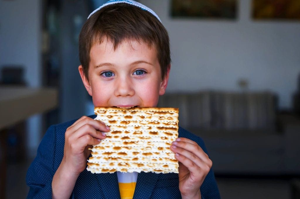A young boy eats a traditional Jewish unleven bread during Passover.