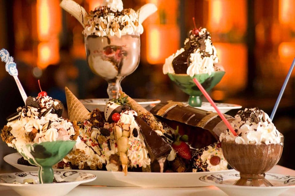 A table is laden with desserts like malts and ice cream dishes at Serendipity 3, one of the best stops on our NYC itinerary with kids.