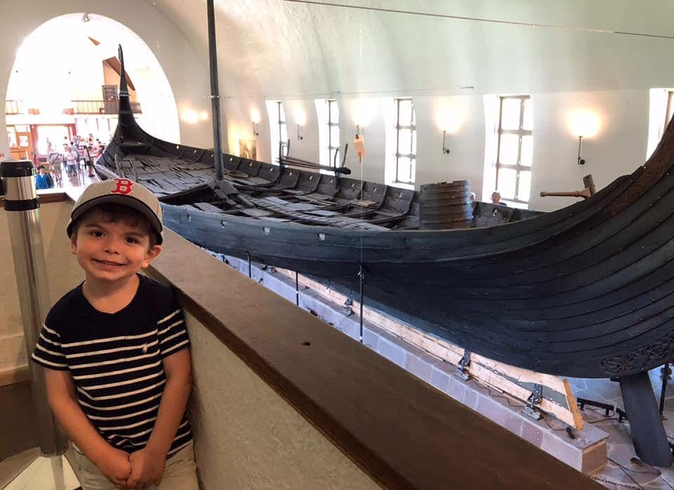 Child in front of a Viking long-ship at the The Viking Ship Museum in Oslo, Norway.