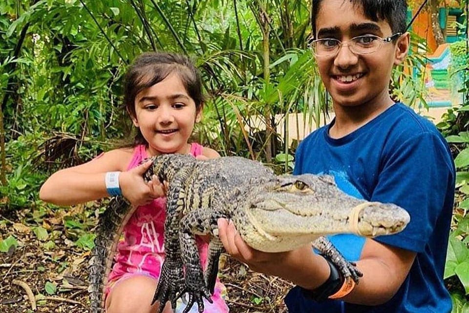 A young girl and a young boy member hold a small crocodile at the Croco Cun Zoo.