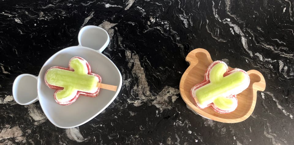 Two homemade cactus-shaped paleta, a Mexican treat. Eating traditional foods is a wonderful way to immerse yourself in a virtual vacation to Mexico.