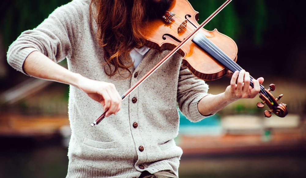 A zoomed in image of a woman's torso as she plays a traditional Irish violin. Music is a great way to engage in this virtual vacation to Ireland.
