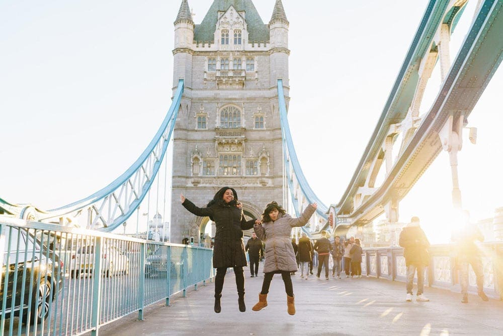 Mother and daughter jumping on tower bridge in London