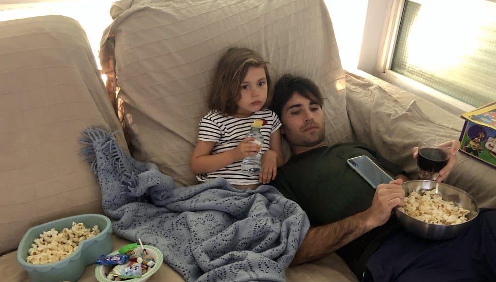 Father and daughter watching a movie with popcorn.