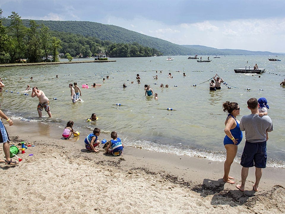 Multple families on the beach at Greenwood Lake, one of the best lakes near New York City for families.