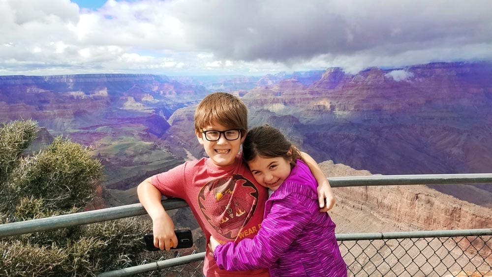 Brother and sister hug in front of the Grand Canyon.