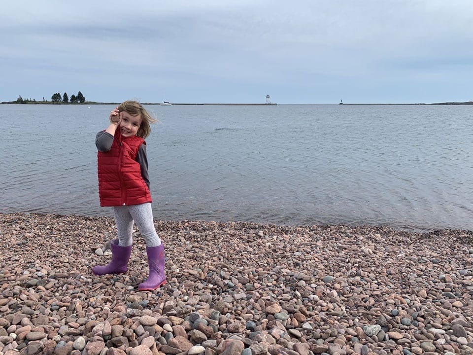 Adorable girl on a pebbly beach in Lake Superior in the US one of the best lakes to visit with your family this summer
