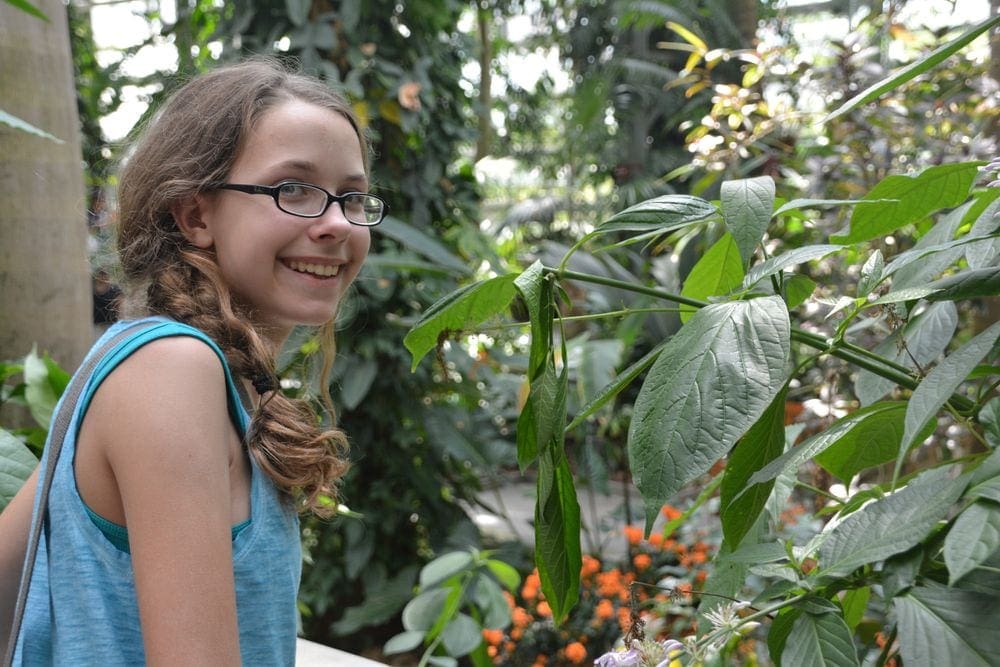 Young girl smiles among the plants and flowers at the U.S. Botanic Garden in Washington D.C.