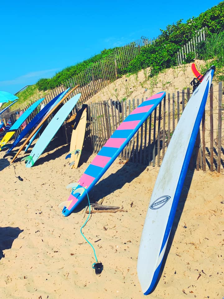 Several colorful surfboards rest along a fence at Montauk Beach.