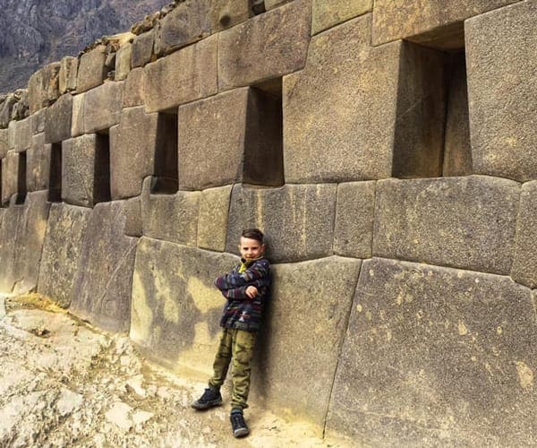 A young boy leans agains an ancient ruin wall near Ollantaytambo.