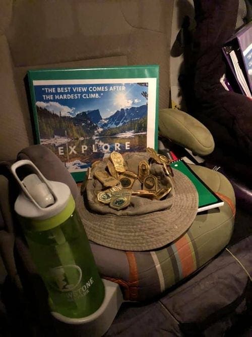 One water bottle, one binder, and one hat sit on a car seat in preparation for a road trip.