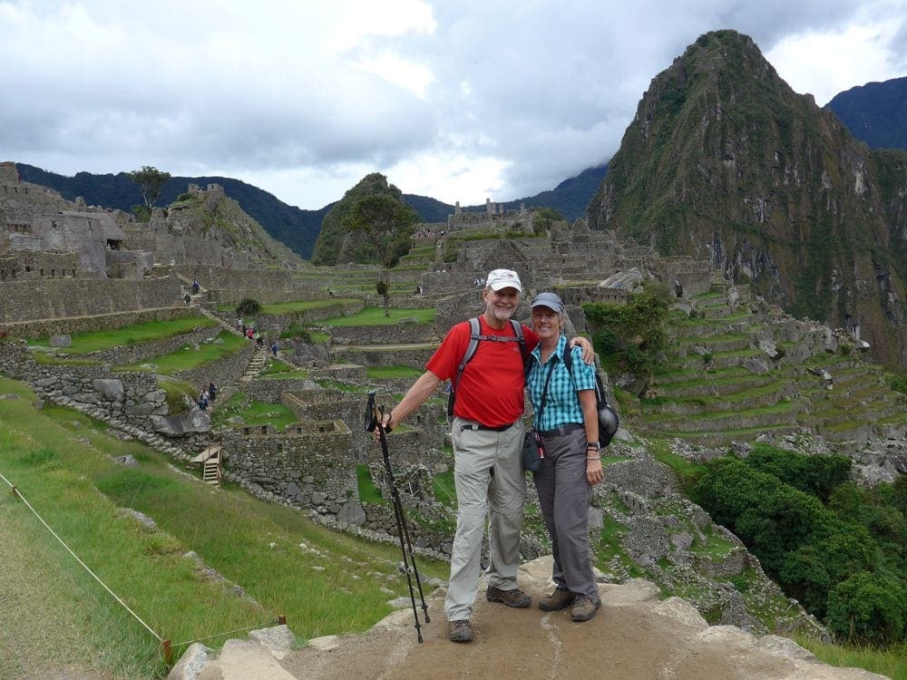 Couple stands above the ruins of Machu Picchu in Peru