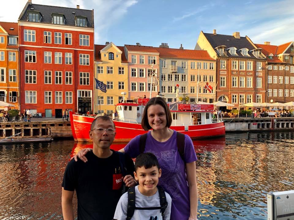 Family in front of colorful row homes by a canal in Copenhagen Denmark, one of the best places to travel with kids in Europe.
